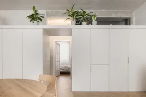 Modern minimalist apartment featuring white concrete walls, white oak floors, and simple white furniture.