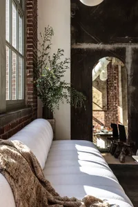 A cozy living room featuring a white sofa, a green plant, and brick walls
