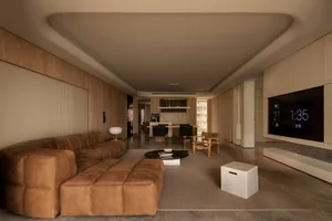 A minimalist living room with a large window overlooking a cityscape, featuring a comfortable sofa, a coffee table, and a boo