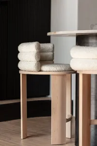 A minimalist wooden stool with a sheep's wool cushion.