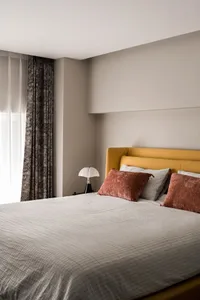 A modern bedroom featuring a yellow upholstered headboard, soft bedding, and a cozy atmosphere.