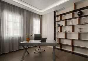 Minimalist modern home office with grey desk, chair, and bookshelf.