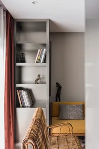 Modern living room with yellow sofa, wooden armchair, and metallic shelves.