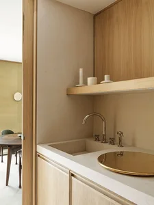 A minimalist kitchen featuring a cement countertop and brass fixtures.