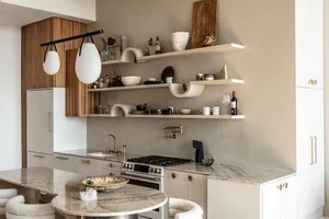 A modern kitchen with white marble countertops and shelves filled with various decorative items and kitchenware.