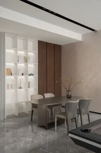 Modern dining room with marble table and chairs, bookshelf with lighting, and wooden walls.