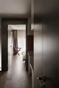 A minimalist bedroom featuring wooden furniture and a large window.