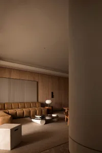 A modern minimalist living room with brown leather furniture, wooden paneling, and marble accents.