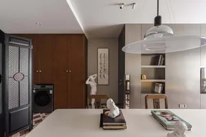 A modern residential kitchen with minimalist design elements, including wooden cabinets, metal accents, and concrete countert