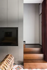 A modern residential staircase with wooden steps and a patterned tiled floor.