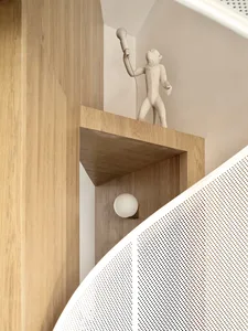 Modern, minimalist interior design featuring a wooden shelf with a monkey-shaped light fixture.