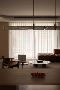 Modern interior design featuring a living room with white curtains, minimalist furniture, and natural light.