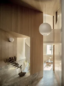 A photograph of a modern hallway featuring wooden elements, marble flooring, and a spherical lamp hanging from the ceiling.
