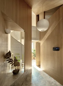 Modern interior design featuring a minimalist walnut staircase corridor with a suspended white spherical light fixture.