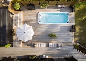Outdoor pool deck with wooden flooring, white umbrella, and surrounding plants and seating.