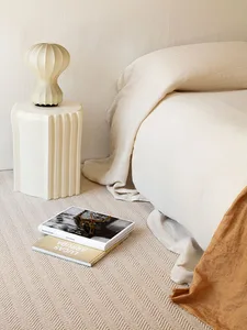 A minimalist bedroom featuring neutral textiles on a bed and a side table.