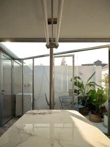 Modern living room featuring glass walls, metal furniture, and potted plants