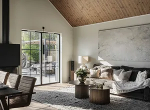 A modern living room with steel finishes, wooden beams, and upholstered furniture.
