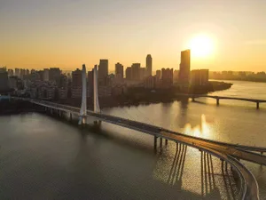 日落時分，現代橋樑橫跨河面，城市景觀映入眼簾。