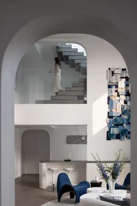 Modern minimalist living space with white walls, blue furniture, and a blue abstract mural on the wall.