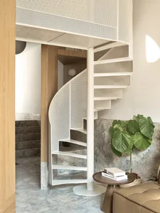 A modern minimalist staircase with white metal and marble steps, featuring a perforated metal railing and a small round table