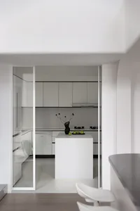 White minimalist kitchen with white cabinets, black accents, and a white island.