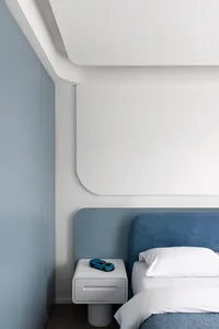 Minimalist bedroom with a blue tiled accent wall, white walls, and white floor.