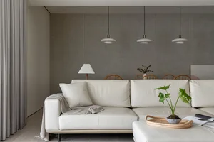 A modern living room featuring a white leather couch, a lamp, a small potted plant, and a tray with a book and a bowl.