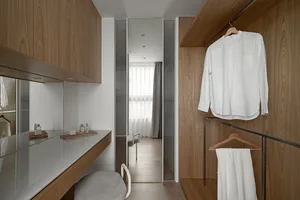 A modern clothing closet with wooden walls and a white dress shirt hanging on a wooden hanger.