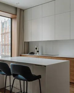 Modern residential kitchen featuring white concrete countertops and wooden cabinets