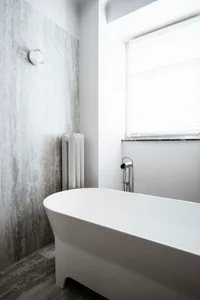 Minimalist bathroom with concrete walls and a white freestanding bathtub.