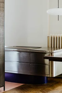 A minimalist interior with a metallic counter featuring sleek drawers and a smooth, curved base.