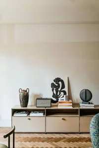A modern living room featuring metal and wood furniture with abstract artwork and books.
