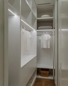 A minimalist closet featuring white storage solutions with shelves and hanging rods.
