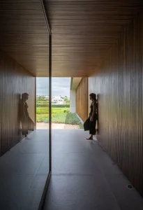 Woman standing in a minimalist living space with wooden paneling.