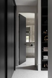 A modern bathroom with grey walls made of concrete, a white vanity, a mirror, and various toiletries.
