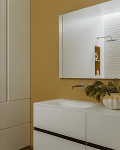 Modern bathroom featuring minimalist interior design with white ceramic tiles and white fixtures.