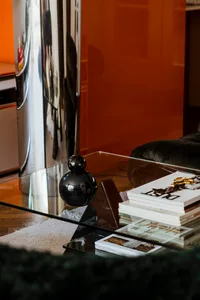 A modern coffee table with glass top and marble base, featuring decorative items and books.