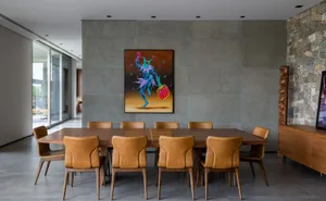 A modern dining room with concrete walls and a wooden dining table surrounded by brown leather chairs.