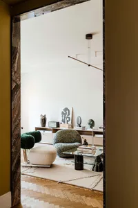 Modern living room with neutral-toned hardwood flooring, glass coffee table, and contemporary furniture.