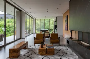 A modern living room featuring wooden furniture, glass panels, and marble accents on the floor and wall.