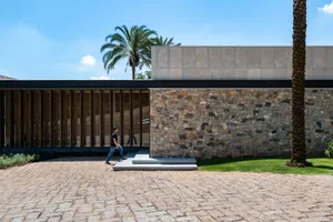 A modern residential exterior featuring stone, glass, and concrete materials.