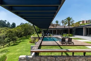 A modern residential outdoor space featuring a pool, lounge chairs, and a lush, green lawn.
