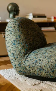 A modern sofa with a blue tweed fabric upholstery, placed on a white rug.