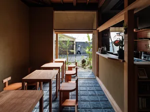 A cozy cafe interior featuring wooden furniture and a small courtyard with potted plants.