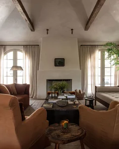A rustic, industrial-style living room with concrete walls, wooden beams, and fabric seating.