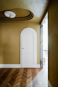 A minimalist interior design featuring an arched white door with a brass handle on a wooden floor with a parquet pattern, ill