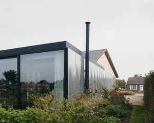 Modern house extension with large glass panels and a chimney