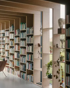 A modern library with tall bookshelves filled with books, sculptures, and plants.