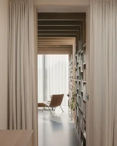 這張圖片呈現一間現代簡約圖書館，配有書架與窗簾。